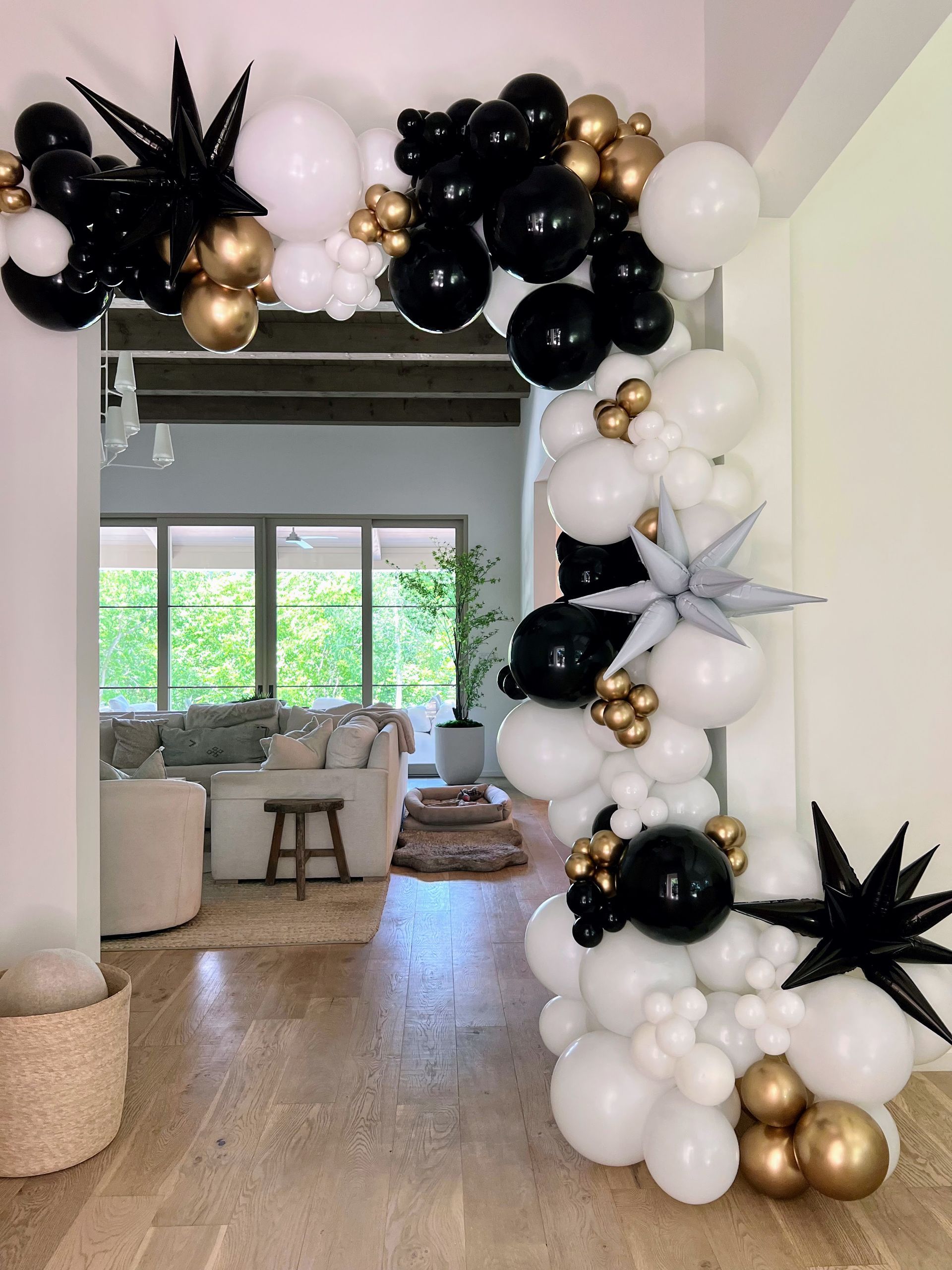 A black and white balloon arch in a living room.