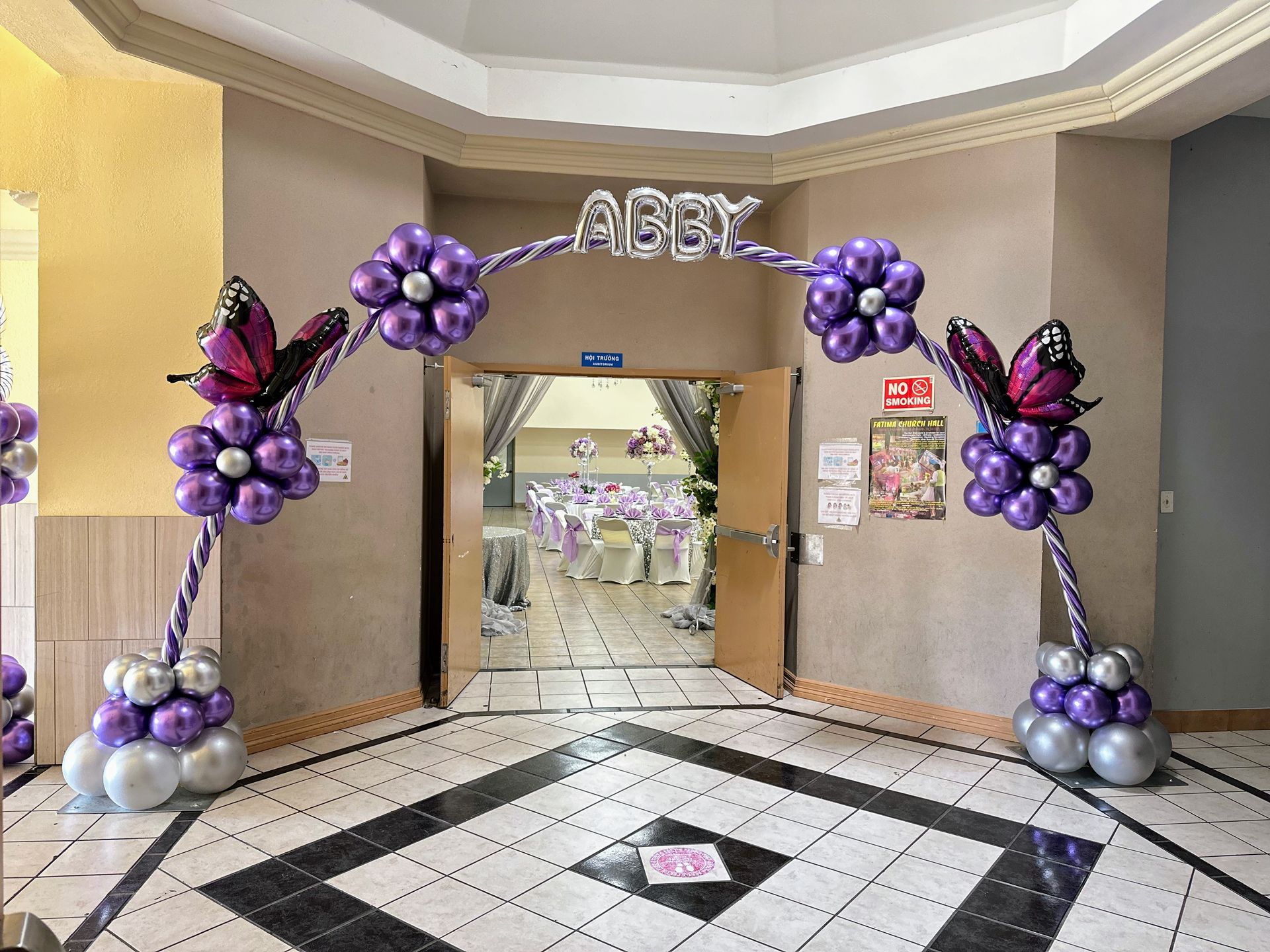 A hallway decorated with purple balloons and butterflies.