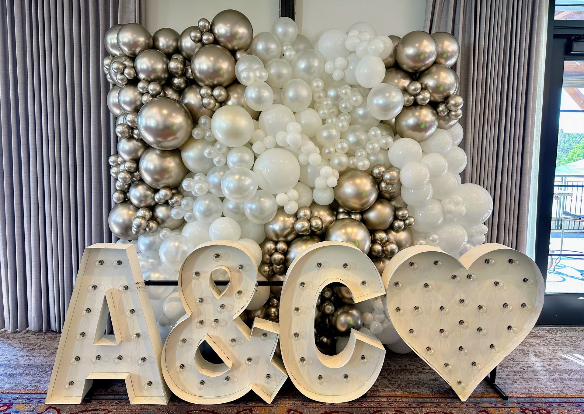 A wall of balloons with the letters a and c in front of it.