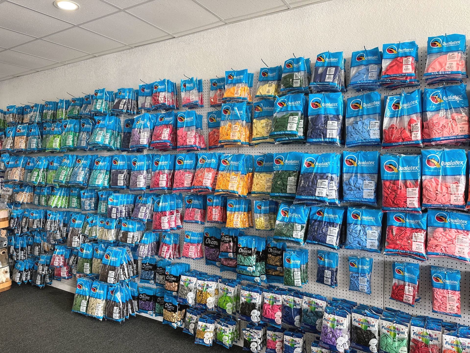 A wall filled with lots of bags of balloons in a store.