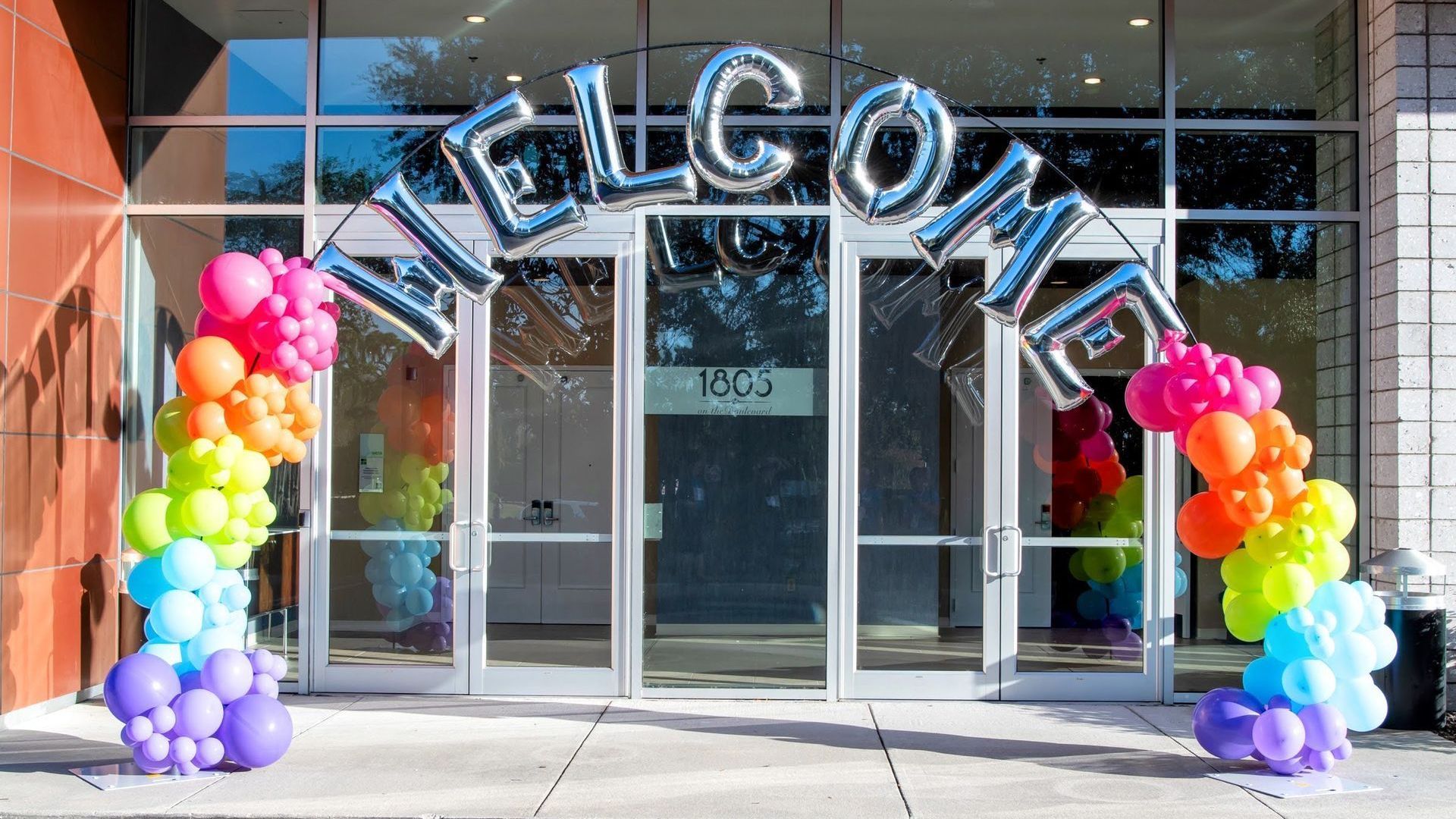 Back to school balloon arch installed at school entrance with rainbow balloon décor and themed accents for welcoming students
