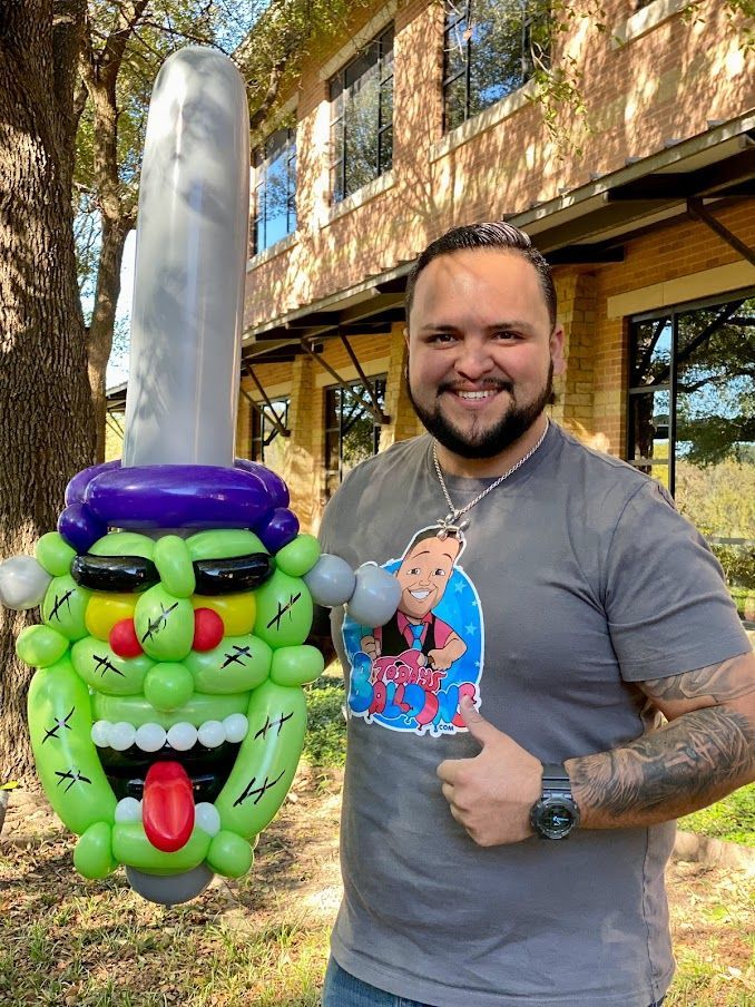 A man is standing next to a balloon sculpture of frankenstein.