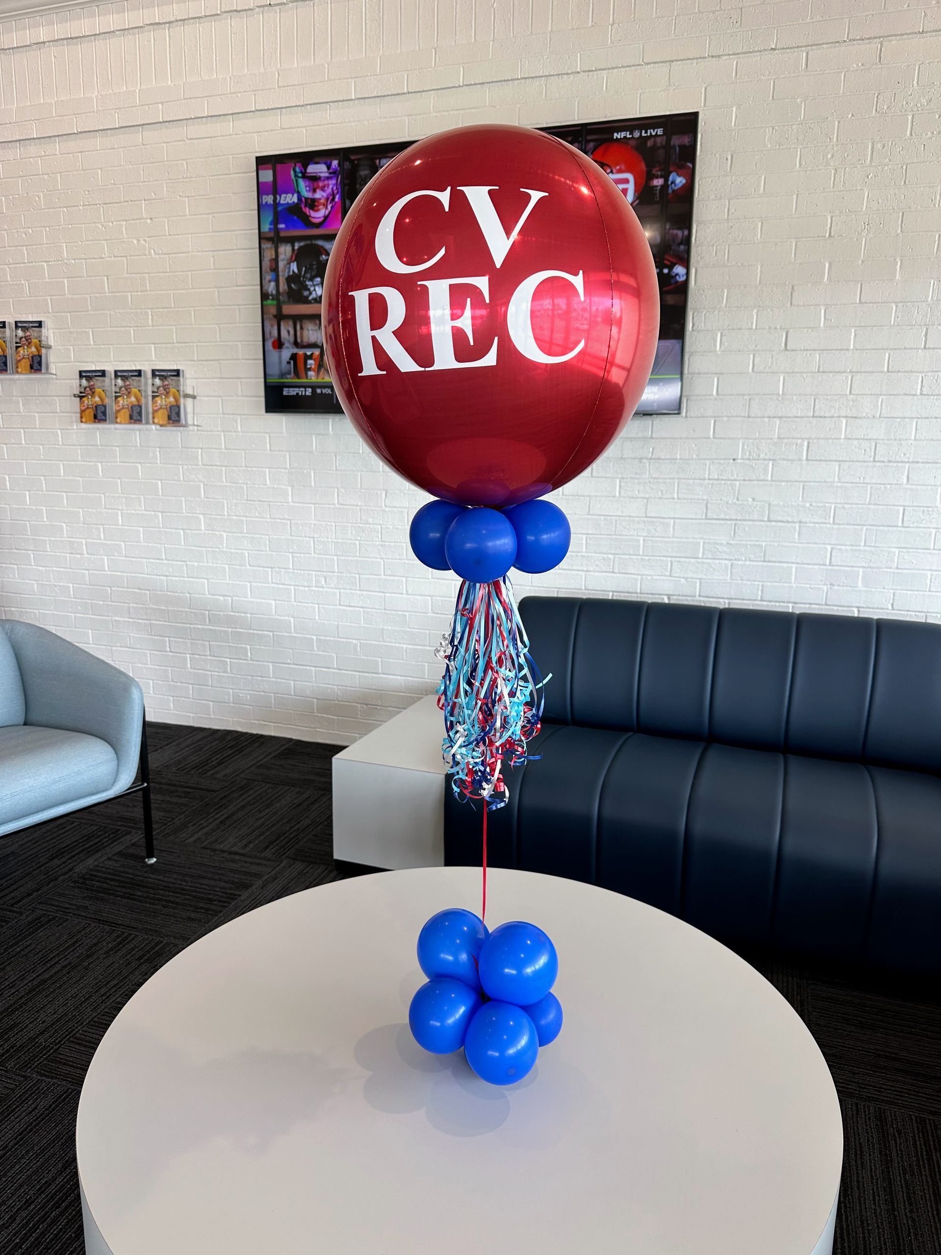 A personalized corporate balloon centerpiece with matching accents on a featured table.