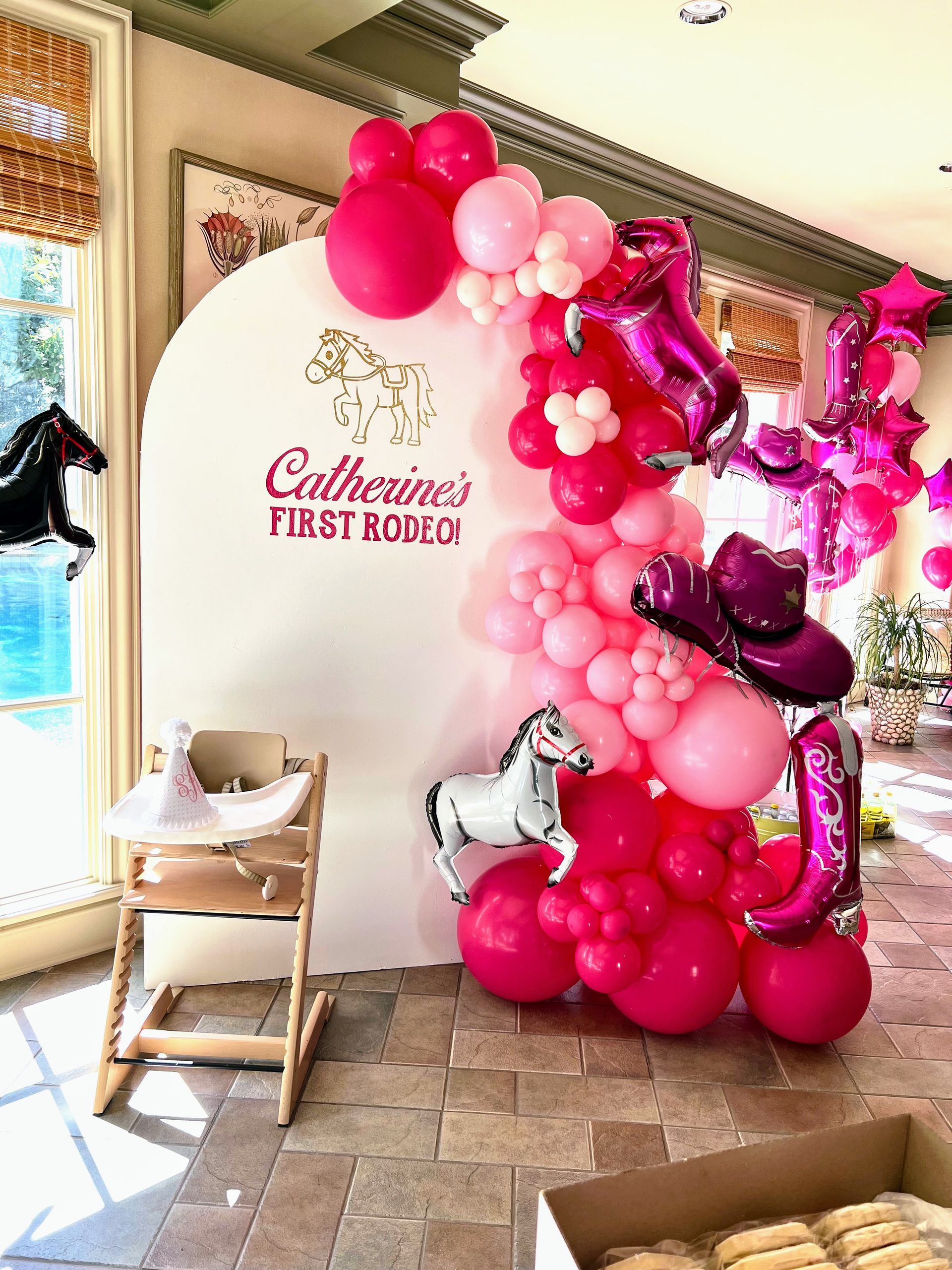A room filled with balloons and a high chair.