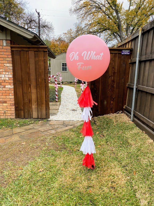 A large pink balloon is sitting in the grass in front of a house.