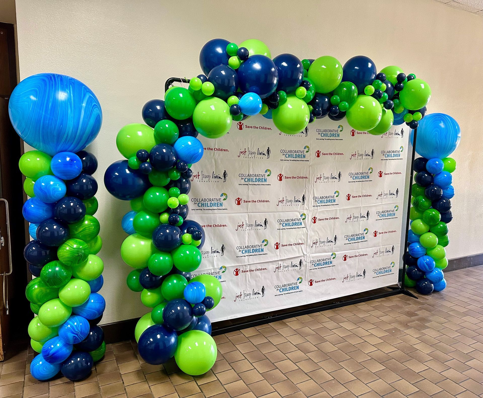 A wall is decorated with blue and green balloons