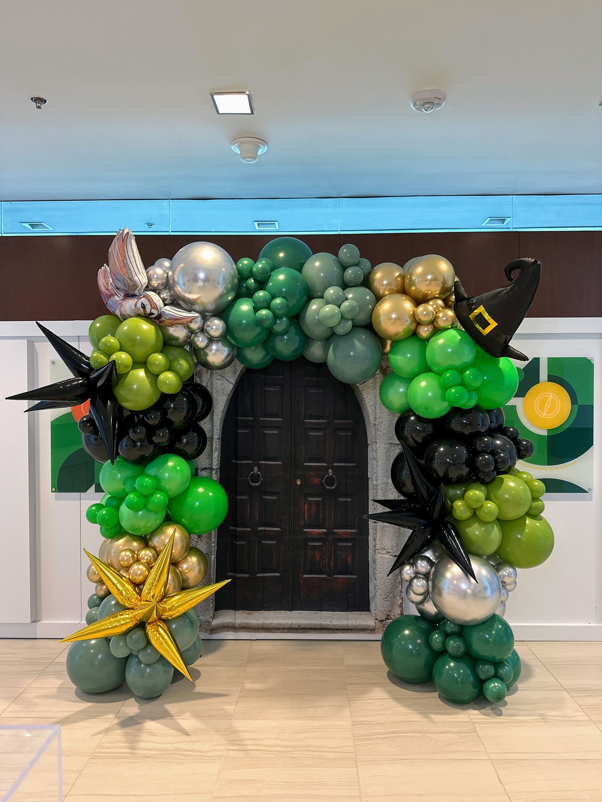 Elegant balloon garland with green, gold, and silver balloons for a formal event backdrop.
