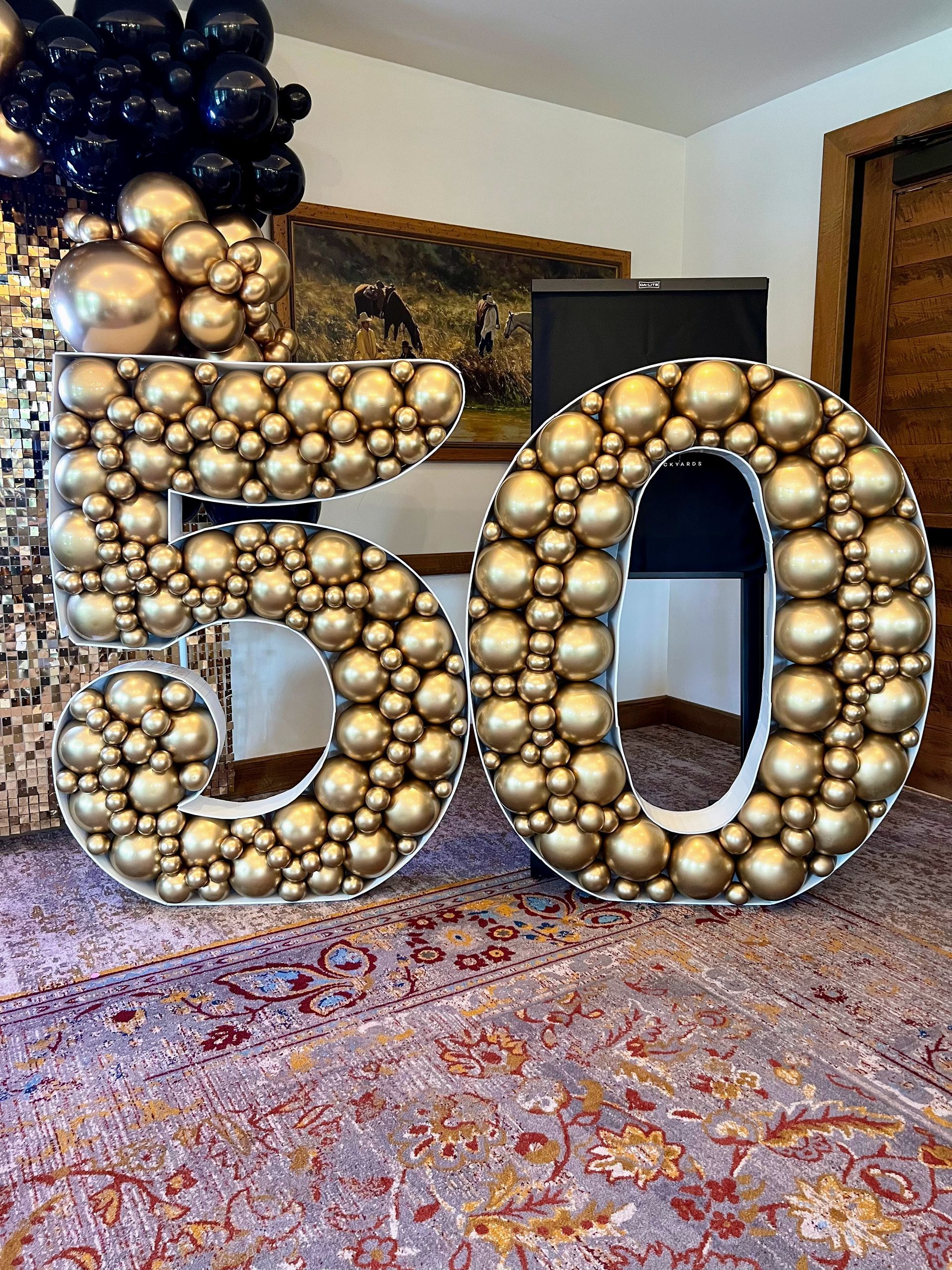 
Luxury gold chrome balloon mosaic '50' sculpture for 50th birthday or anniversary. Black & gold backdrop. Event decor.