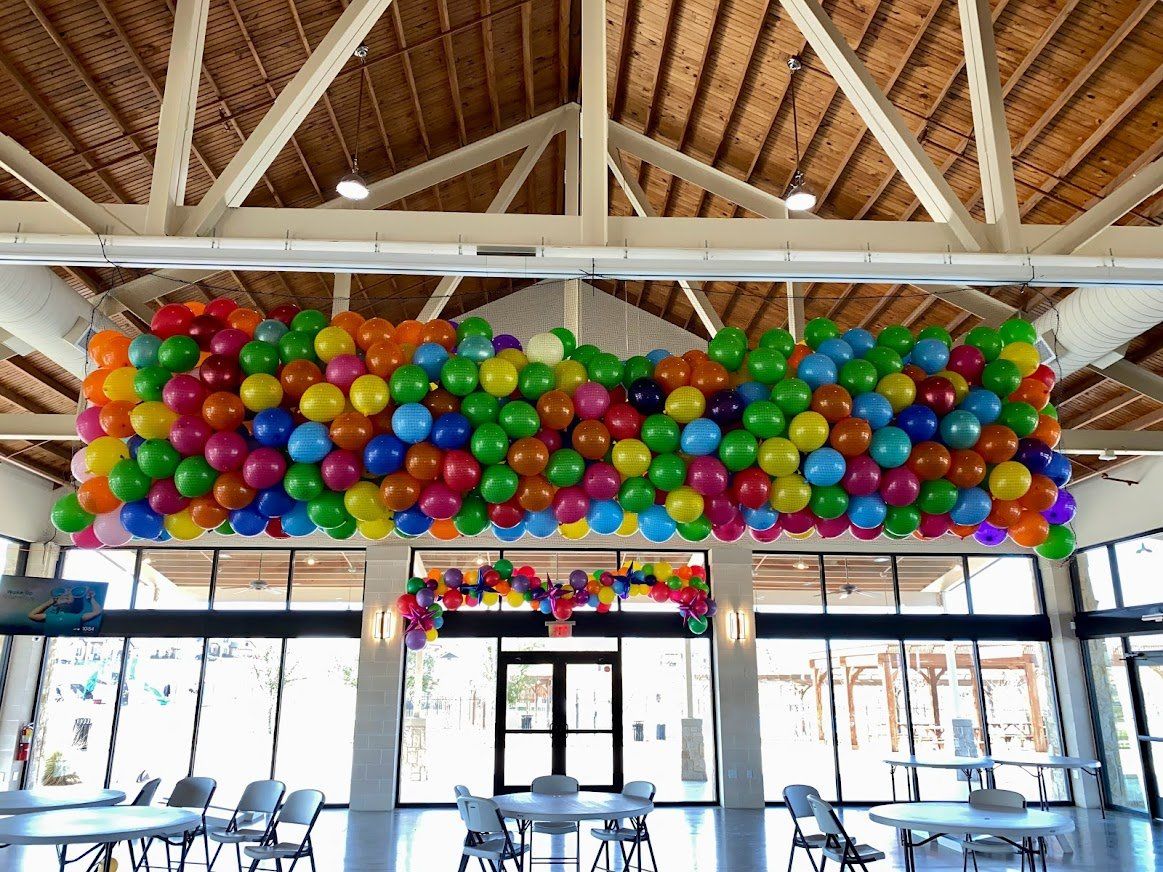A bunch of colorful balloons are hanging from the ceiling of a room.