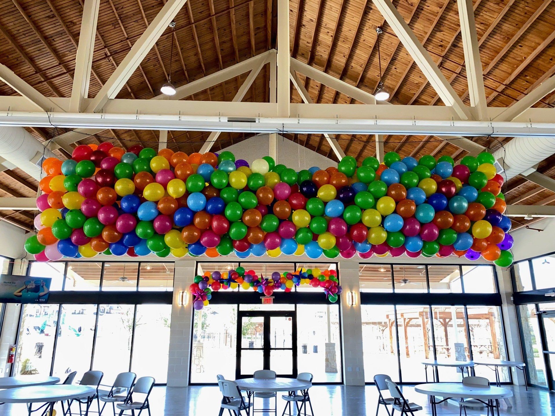 A bunch of colorful balloons are hanging from the ceiling of a room.