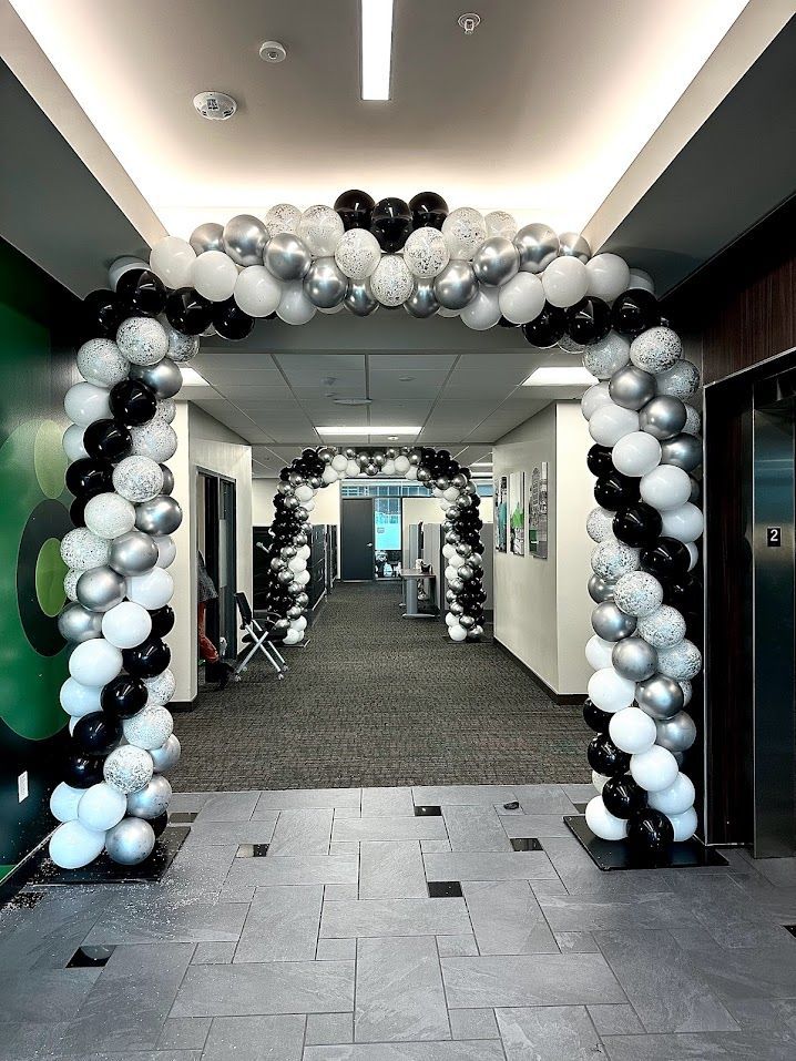 A hallway decorated with black , white and silver balloons.