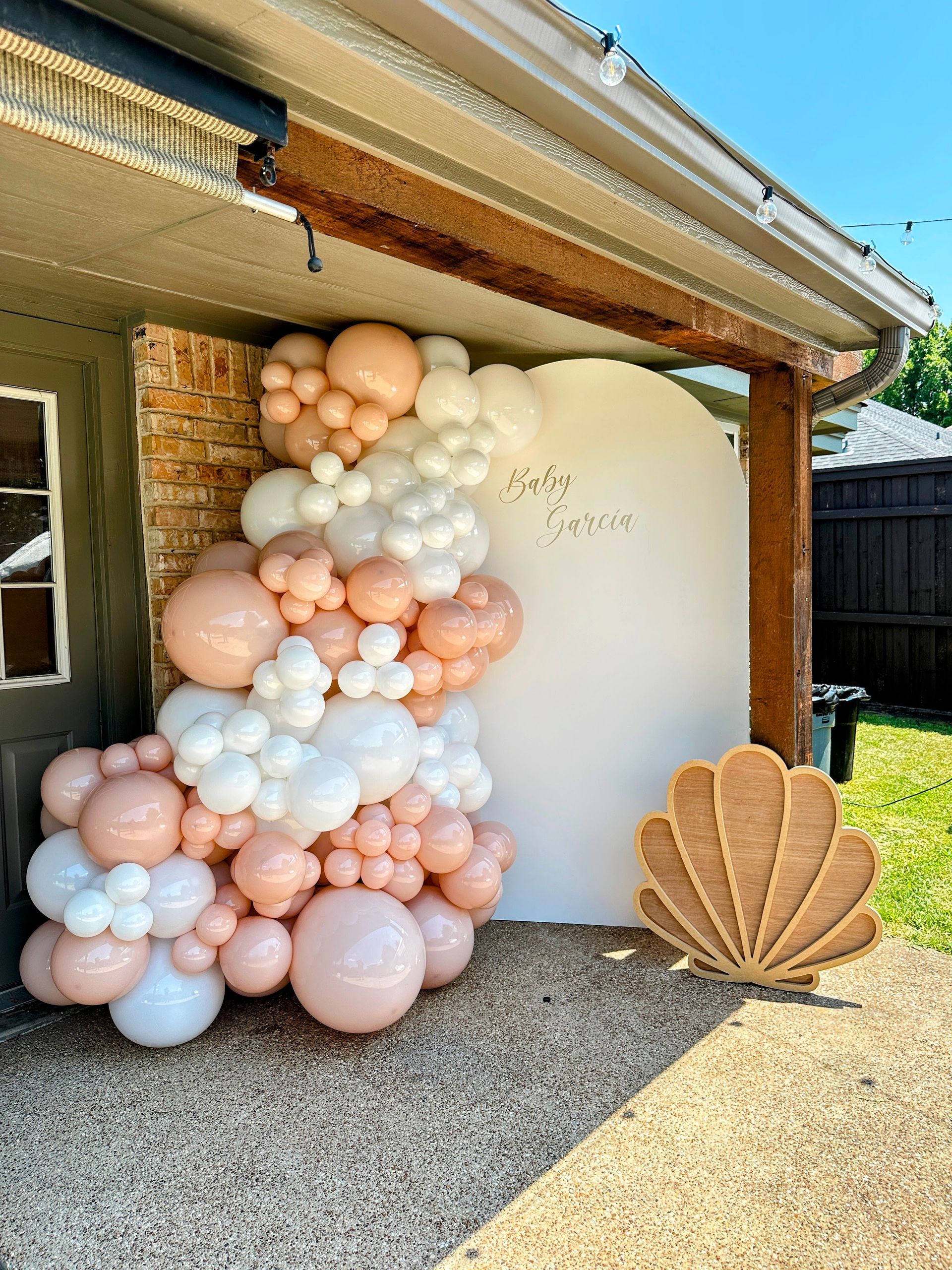 Balloon garland installation featuring neutral tones styled around a backdrop for outdoor event décor