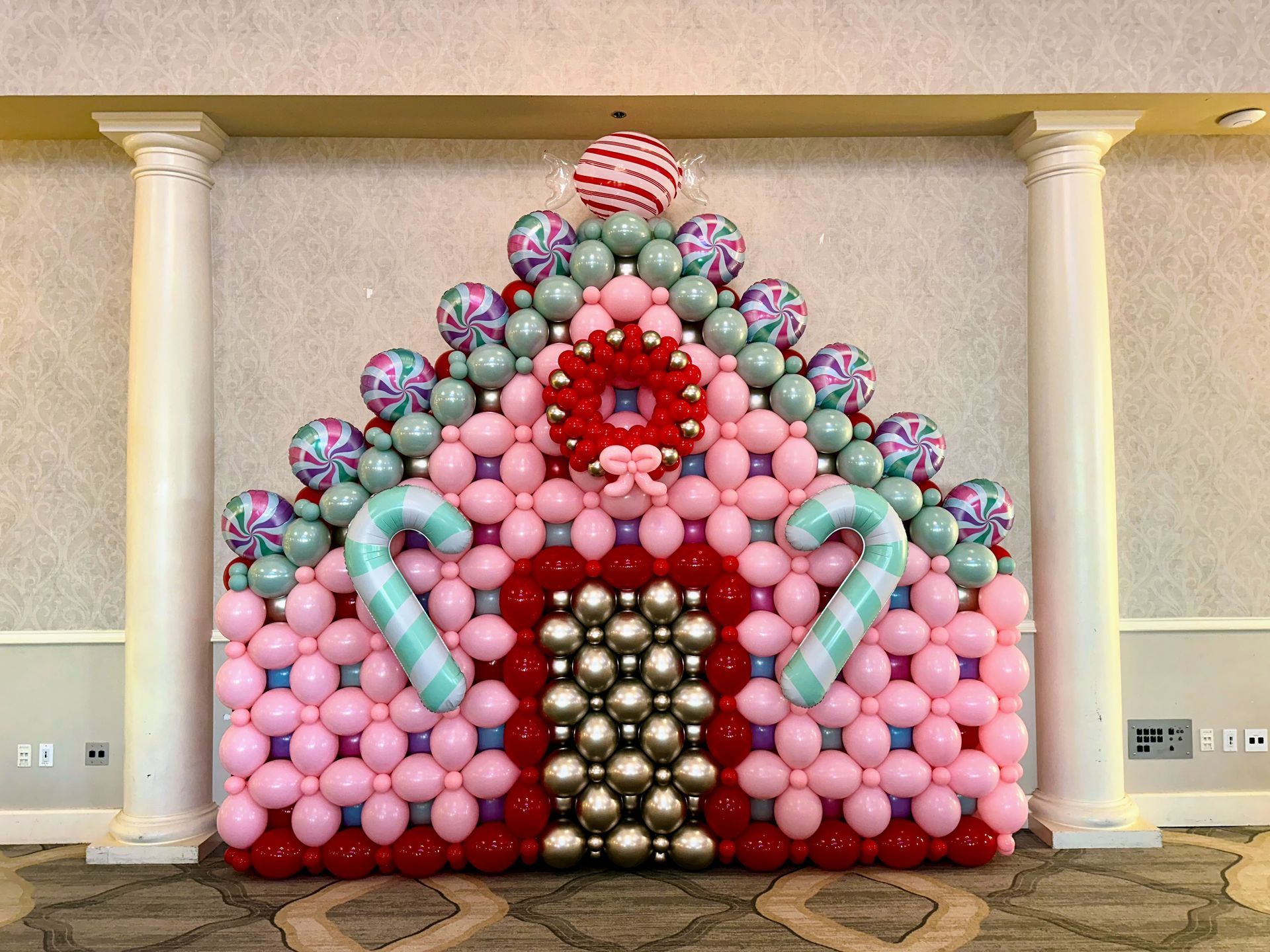 Christmas balloon décor featuring pastel pink, mint, and metallic balloons arranged in a festive holiday backdrop
