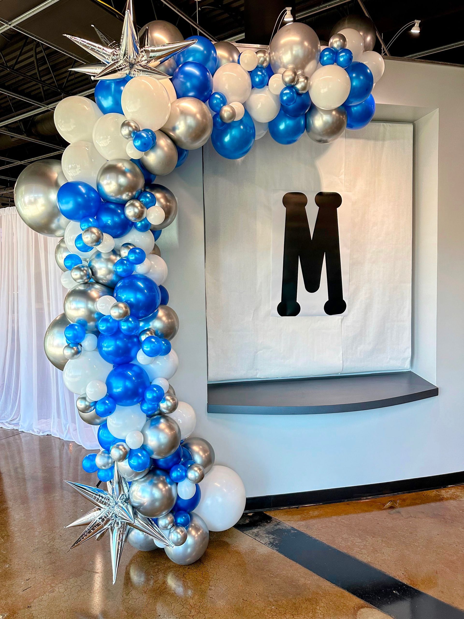 A room filled with blue , white , and silver balloons.