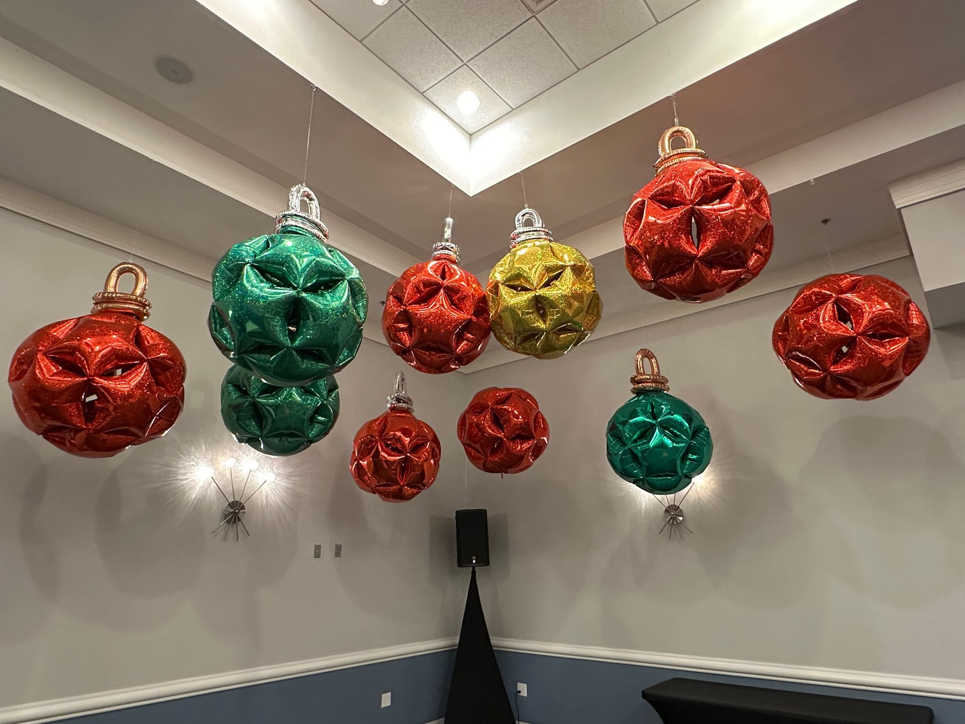 Hanging Christmas ornament balloon décor with red, green, and gold balloons suspended for festive indoor holiday events