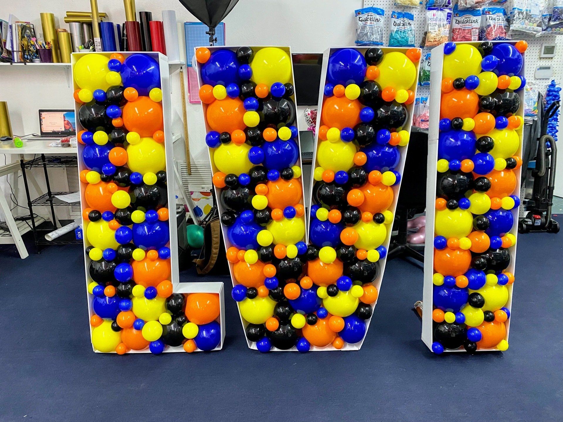 A large letter w made of balloons in a room.
