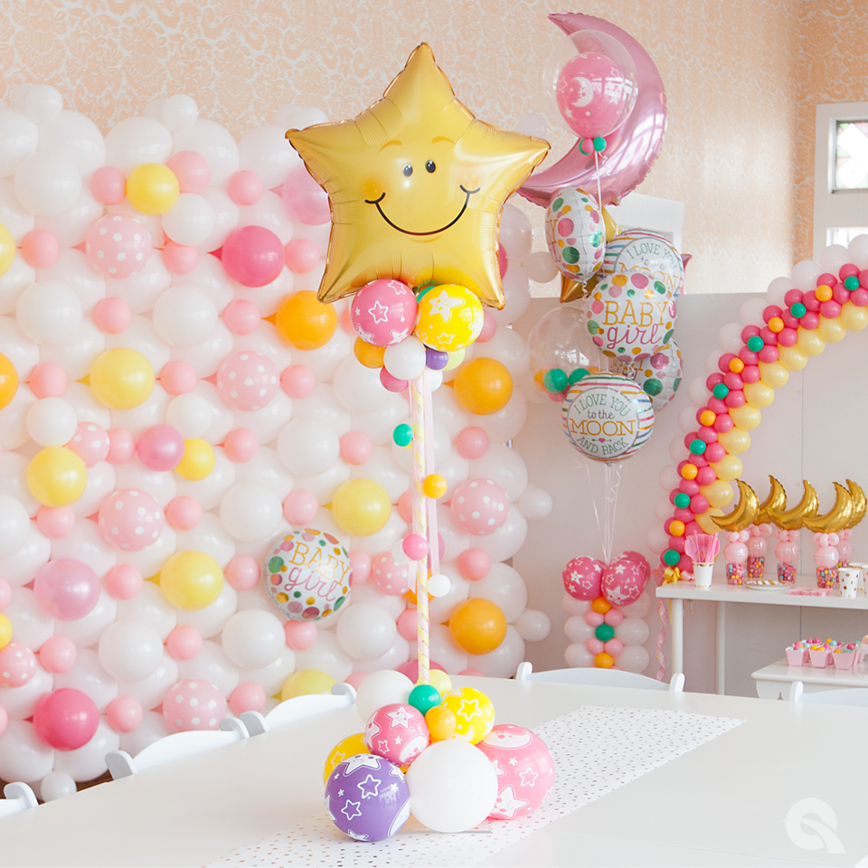 A balloon with a smiley face on it is sitting on a table in front of a wall of balloons.