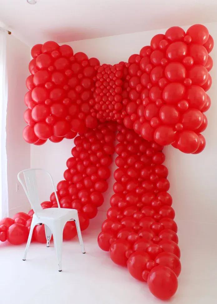 Oversized red balloon bow mounted on a wall