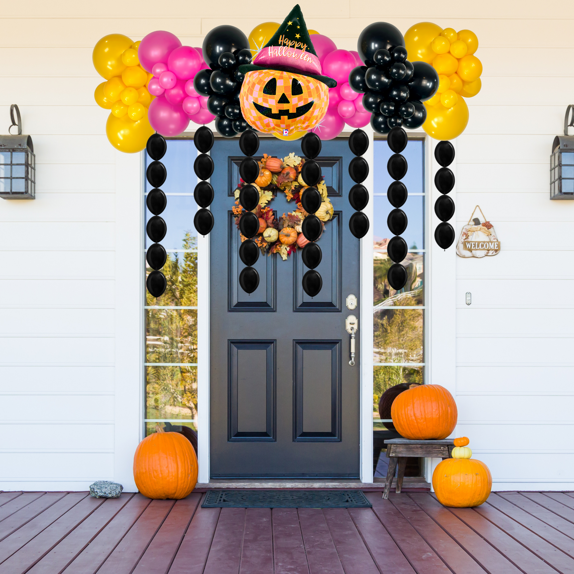 Halloween themed balloon garland in yellow, pink and black balloons with a pumpkin balloon centered and pearls over doorway