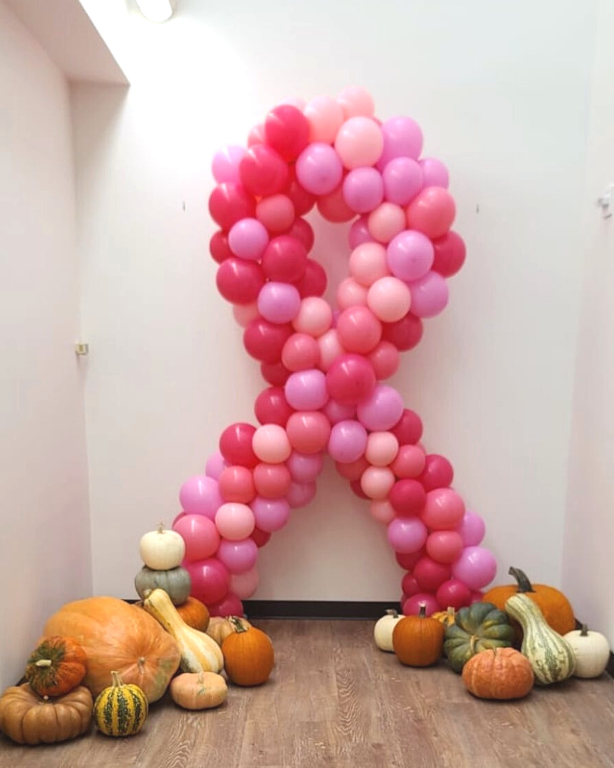 A ribbon made of pink balloons is surrounded by pumpkins