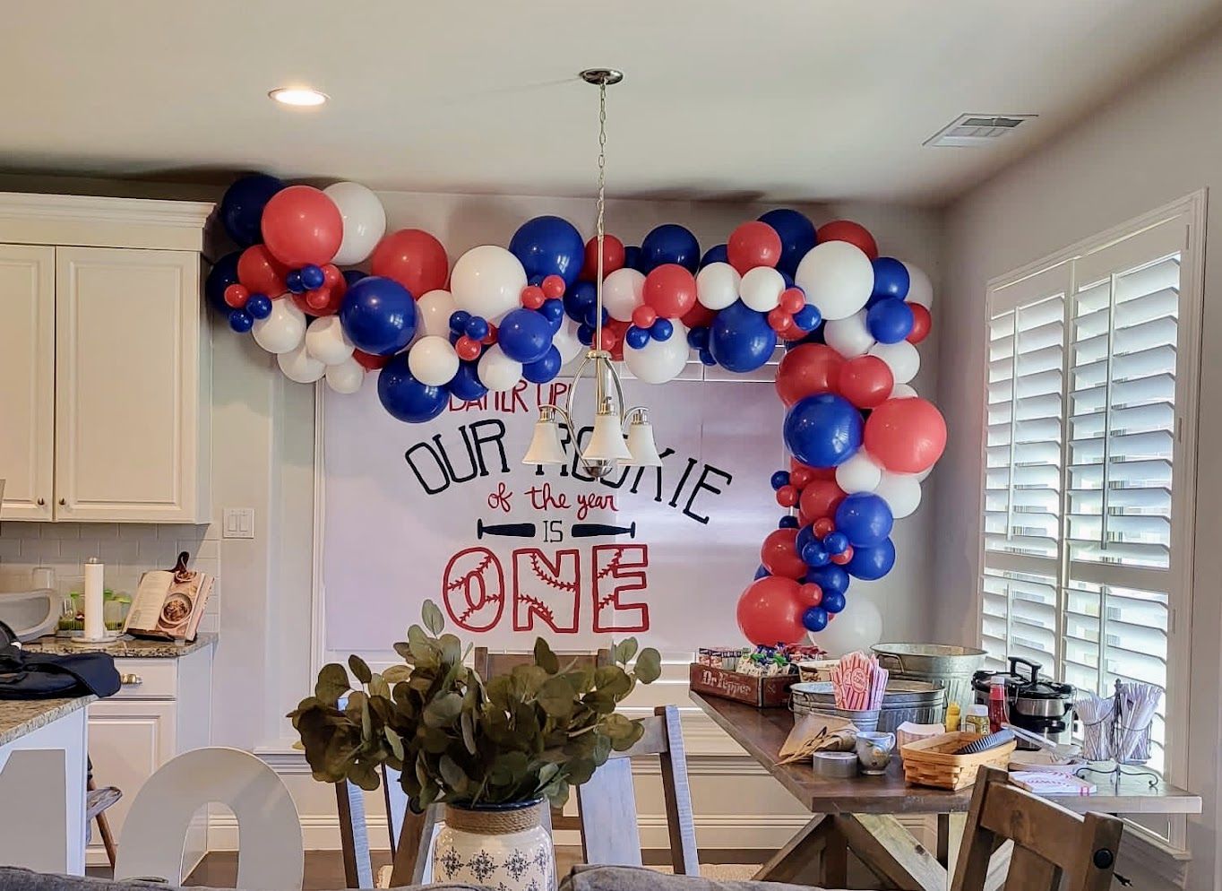 A room decorated with red , white and blue balloons for a baby 's first birthday.