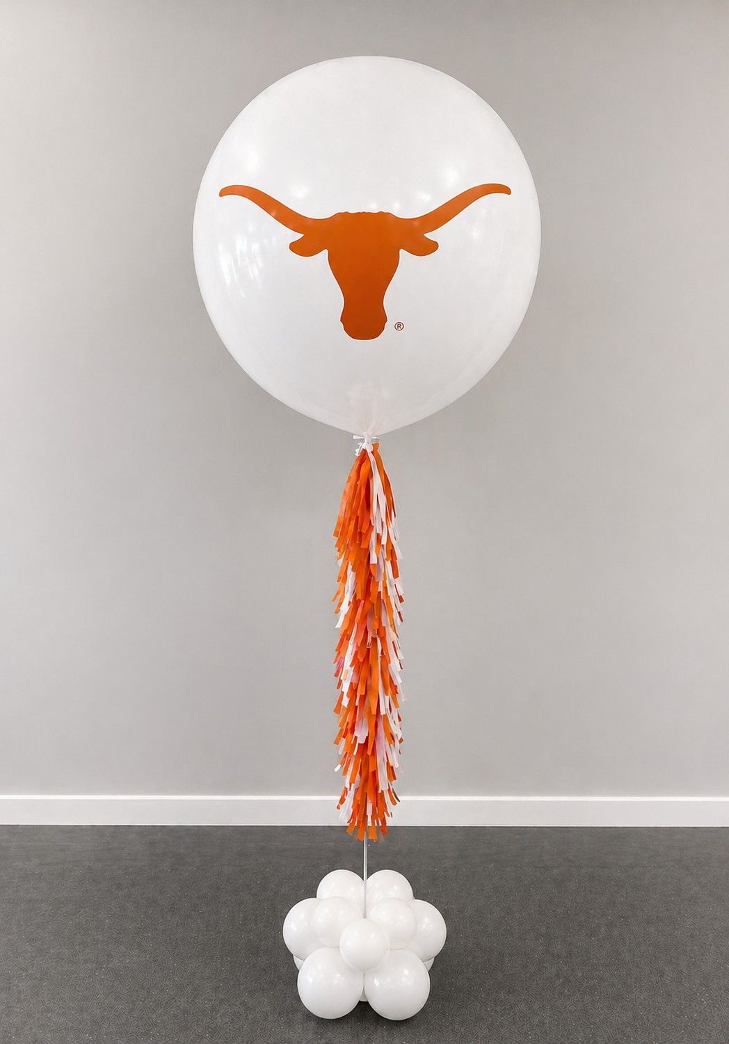 A jumbo helium balloon personalized with University of Texas  logo and color, with matching colored tassels..