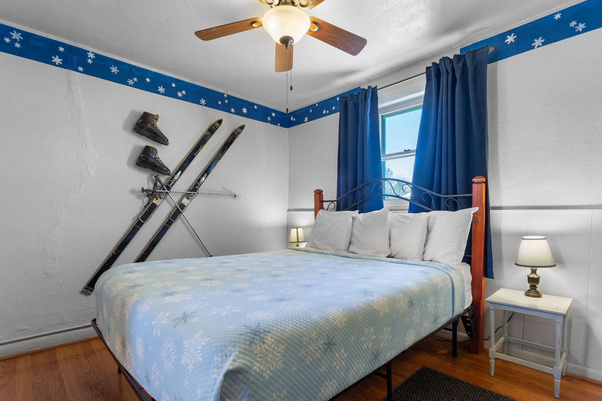A hotel room with two double beds, featuring green and white striped bedding, set against pink walls and a ceiling fan.