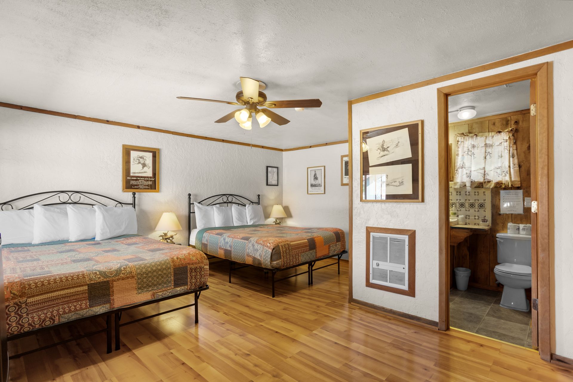 A motel room featuring a bed, dresser, table, and an open doorway to the bathroom.