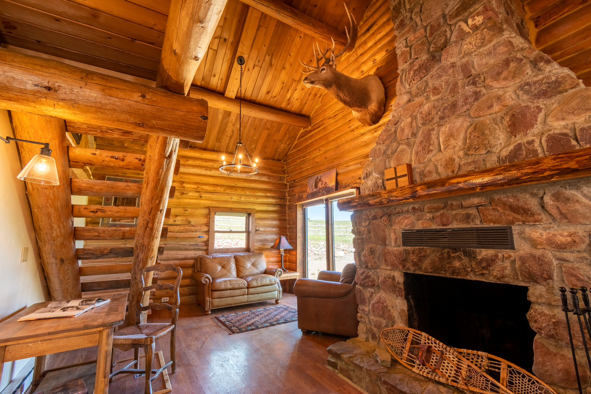 Cozy cabin living room with a stone fireplace, log walls and ceiling.