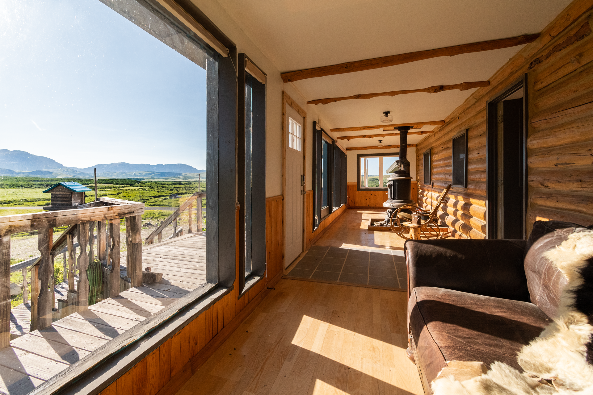 Interior shot of a cabin hallway with large windows overlooking a scenic landscape.