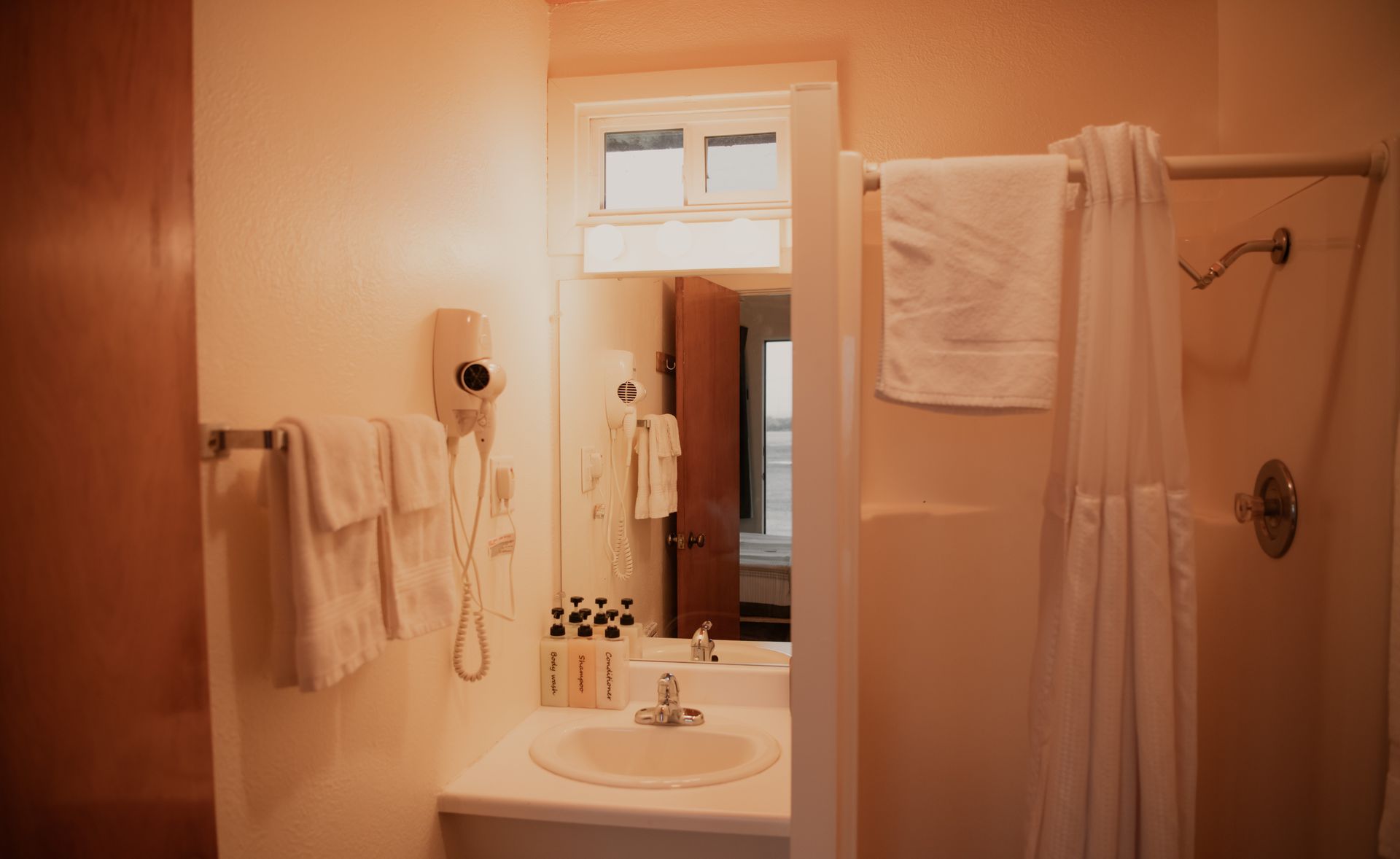 Bathroom interior with sink, mirror, shower, and towels. Neutral color palette.