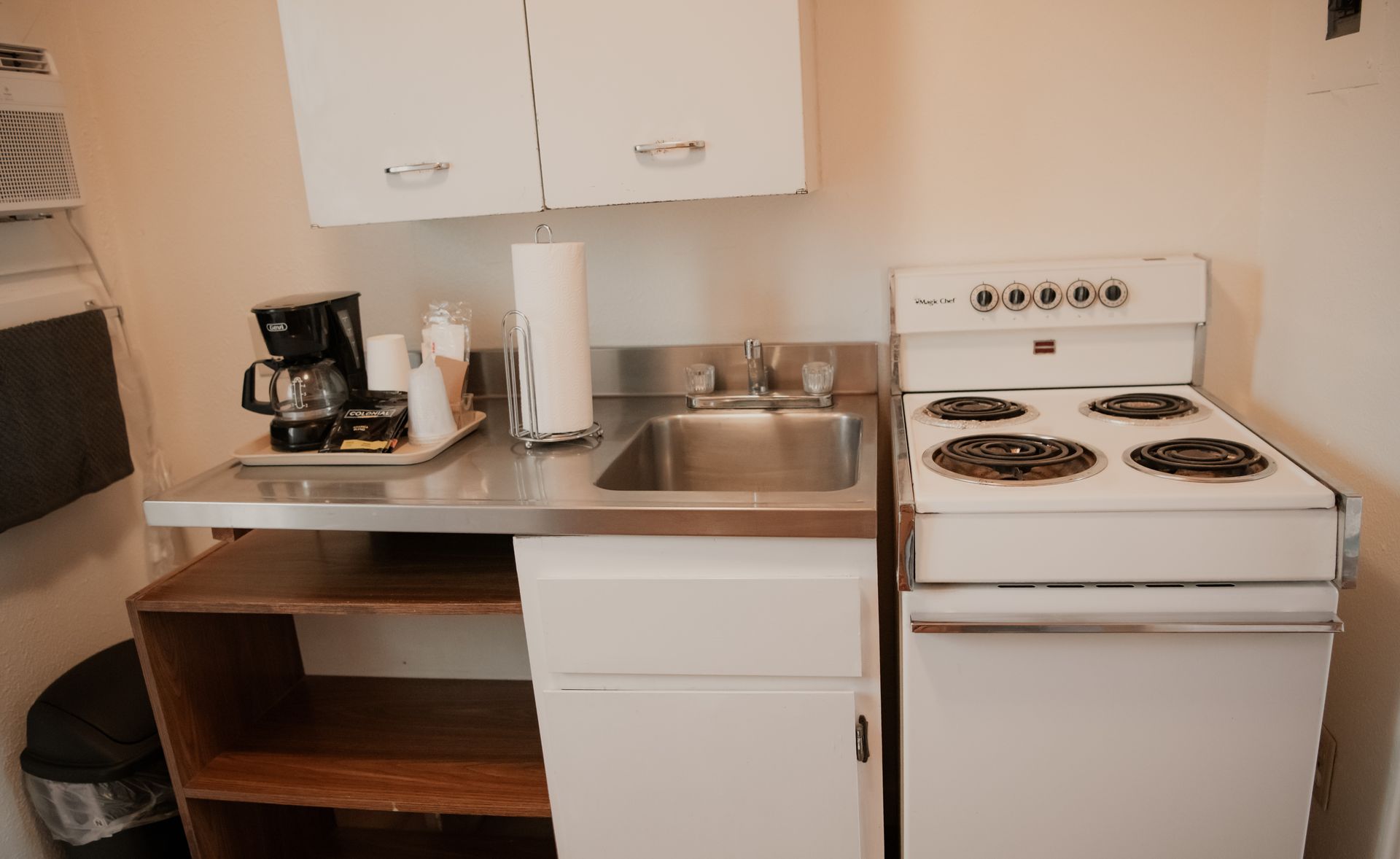 Small kitchen with white appliances, cabinets, and a sink. A coffee maker sits on the countertop.