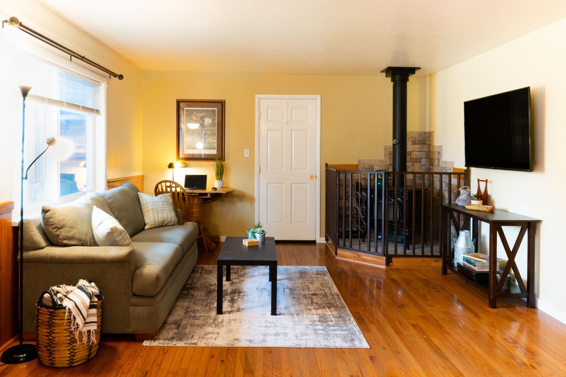 Cozy living room with green couch, fireplace, TV, and hardwood floors.