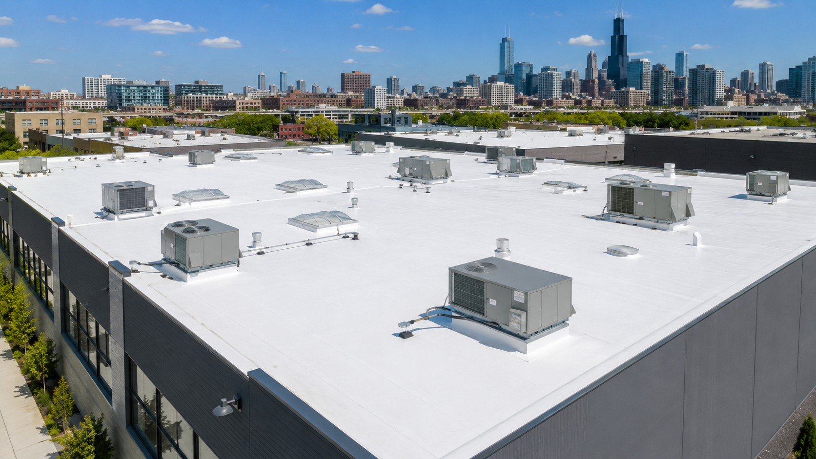 White industrial rooftop with vents, overlooking a city skyline under a clear blue sky