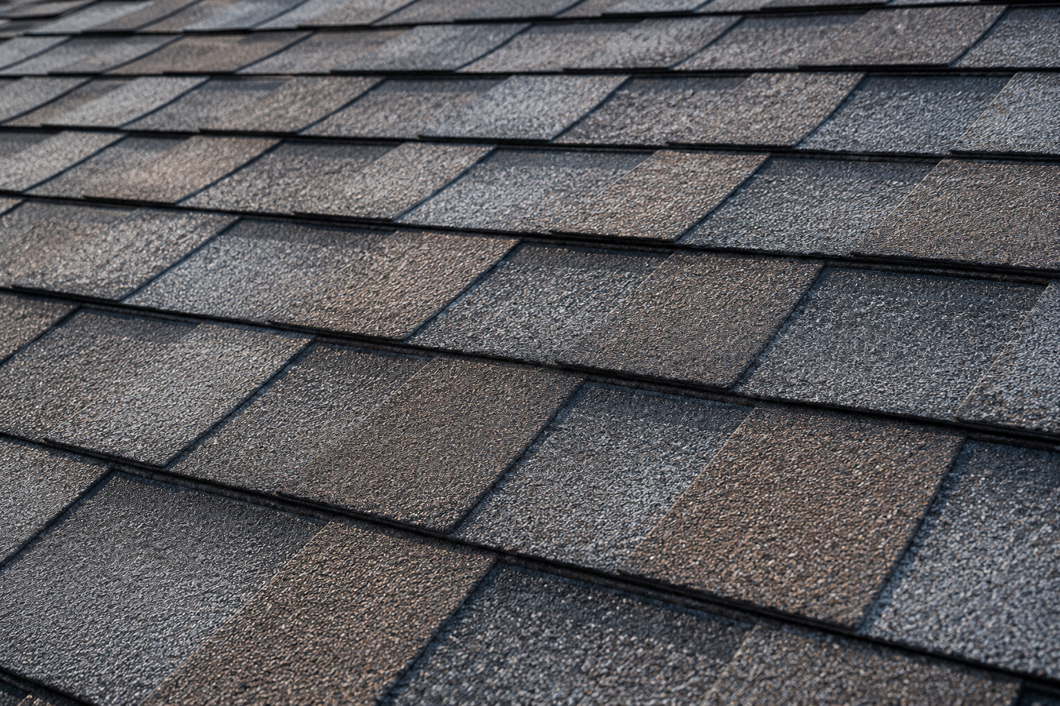Close-up of layered gray asphalt roof shingles with a textured, weathered pattern