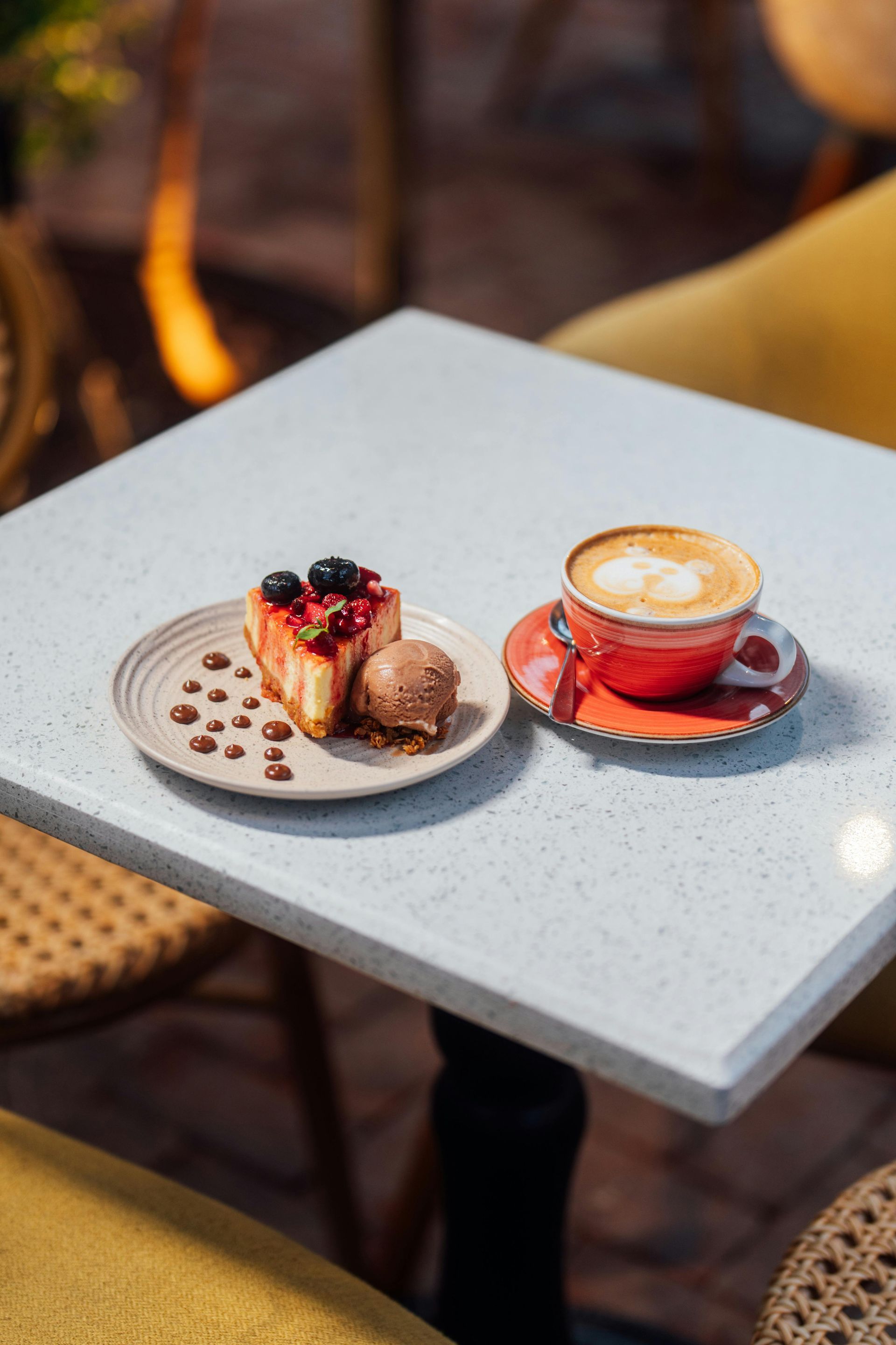 Een stuk cheesecake en cappuccino op tafel; als dessert een portie ijs, koffie met schuimkunst.