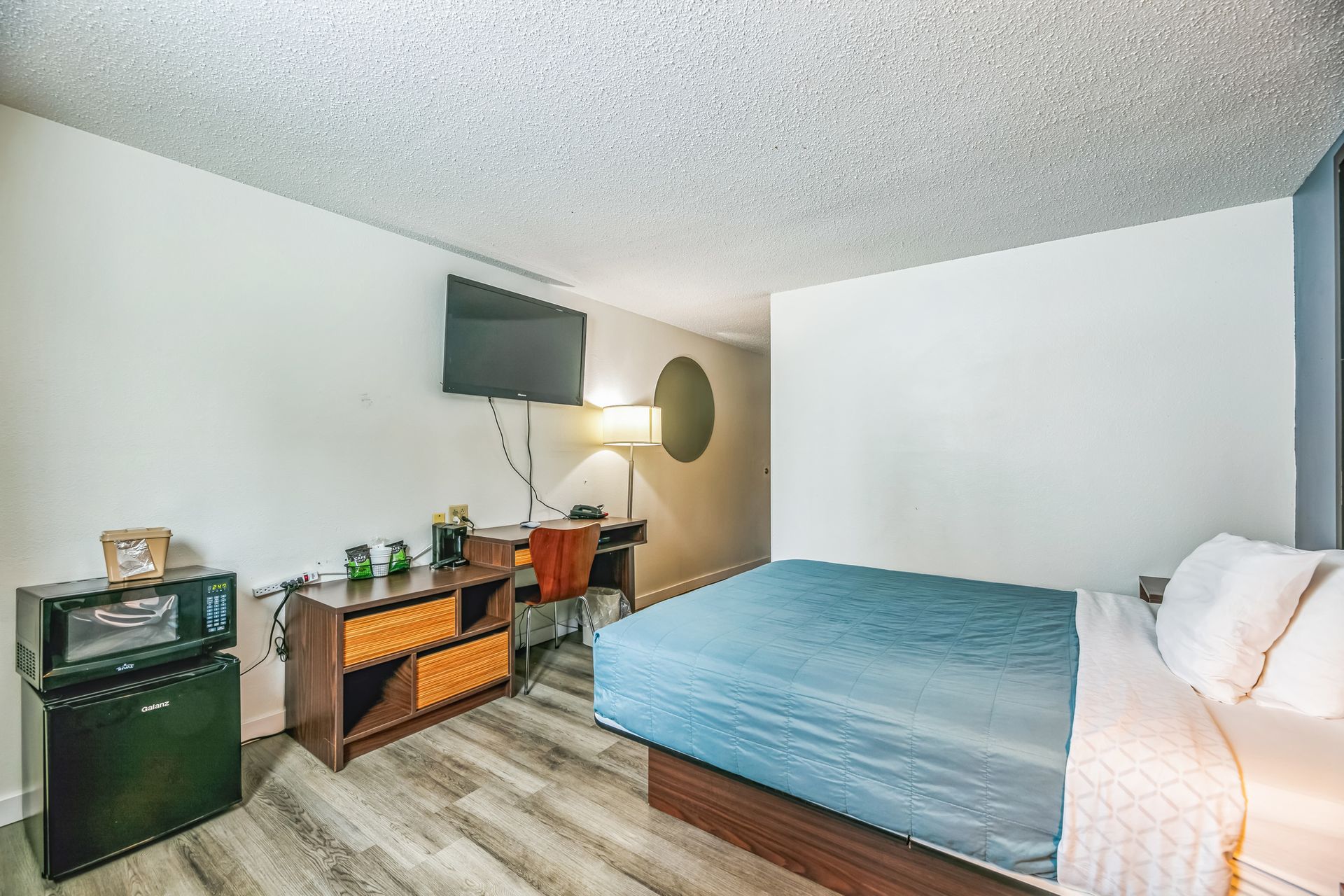 Hotel room with bed, desk, microwave, and mini-fridge.