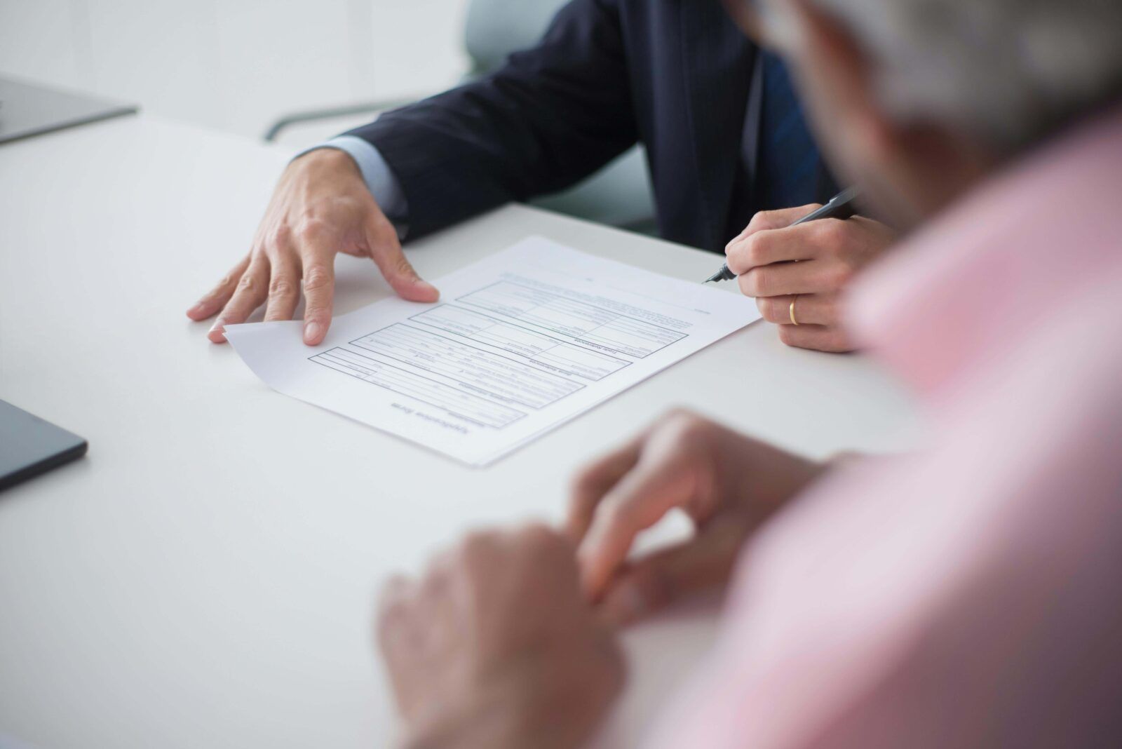 Two men are sitting at a table looking at a piece of paper.