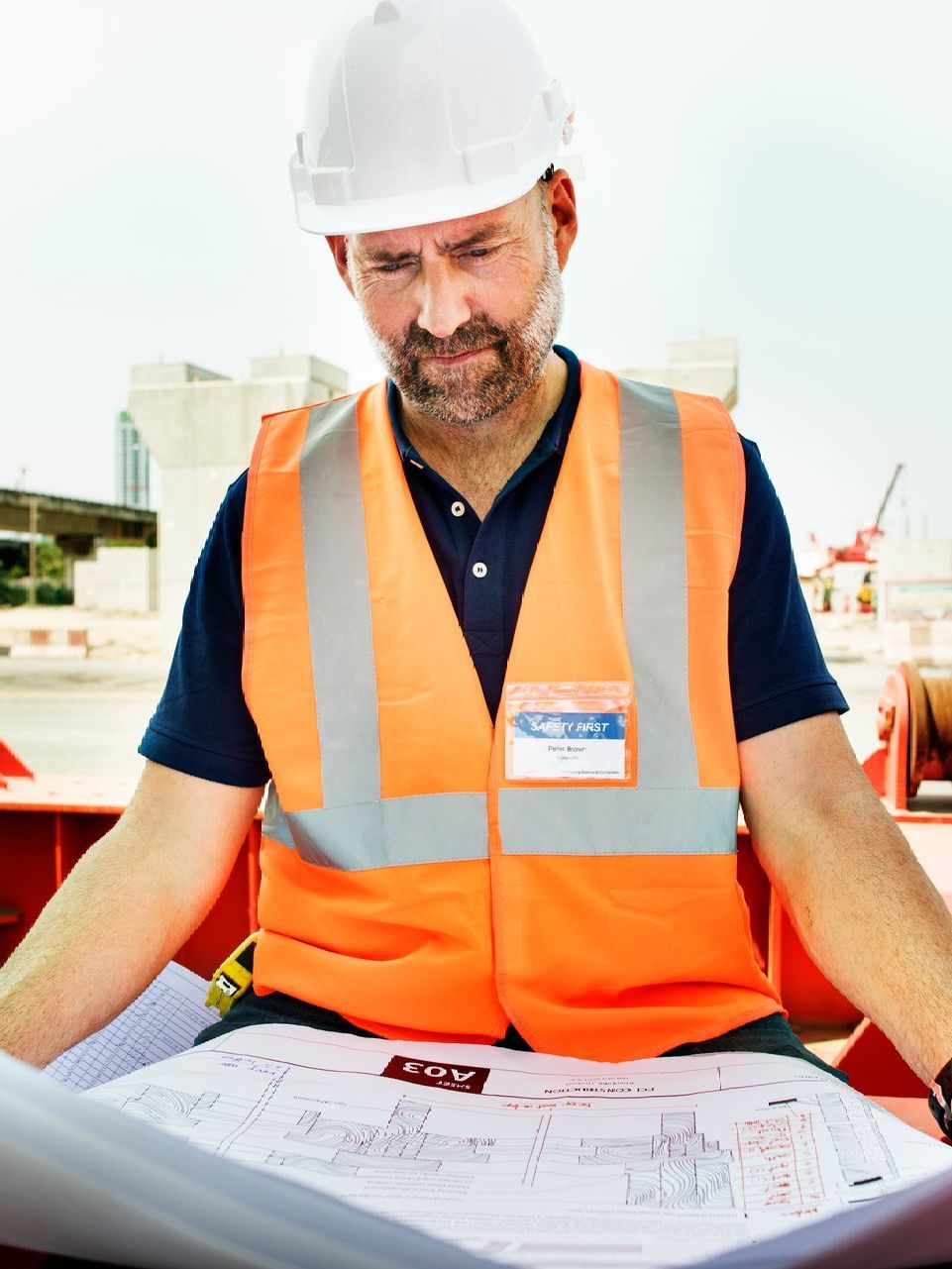 A man wearing a hard hat and gloves is working on a roof.