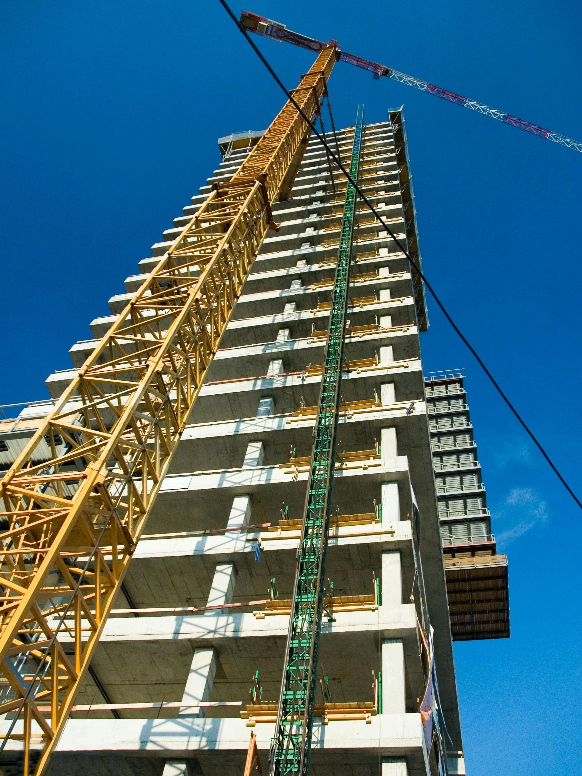 A tall building under construction with a crane in the foreground