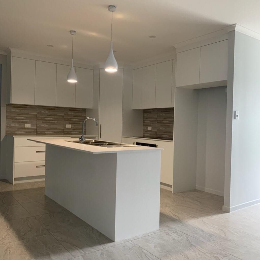A Kitchen With White Cabinets And A Large Island In The Middle — Cross Cabinets In Chevallum, QLD
