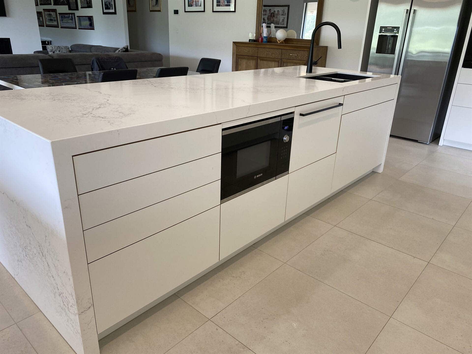 A Kitchen With White Cabinets And A Large Island With A Microwave Oven — Cross Cabinets In Chevallum, QLD