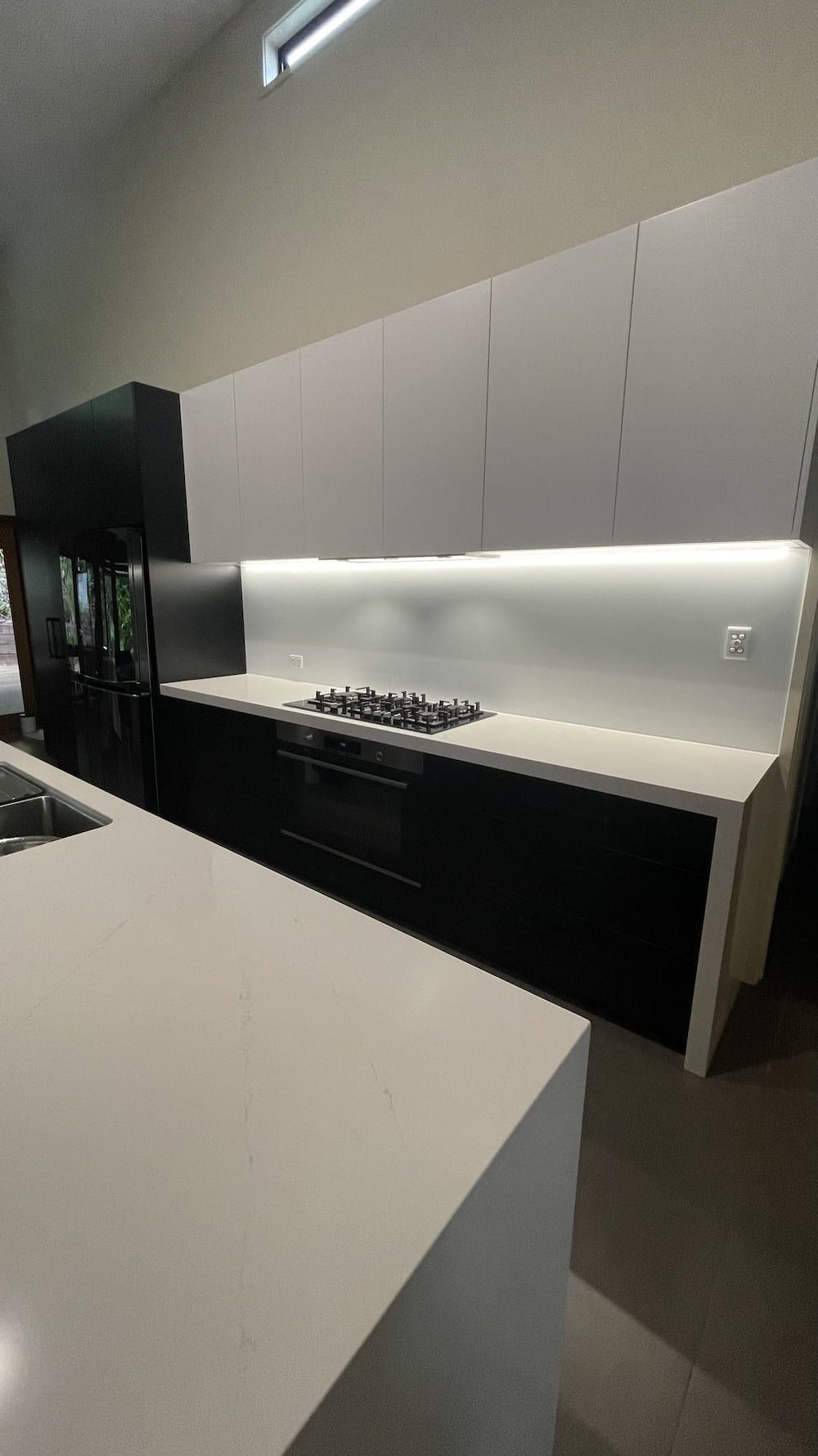 A Kitchen With Black Cabinets And White Counter Tops And A Stove Top Oven — Cross Cabinets In Caloundra, QLD