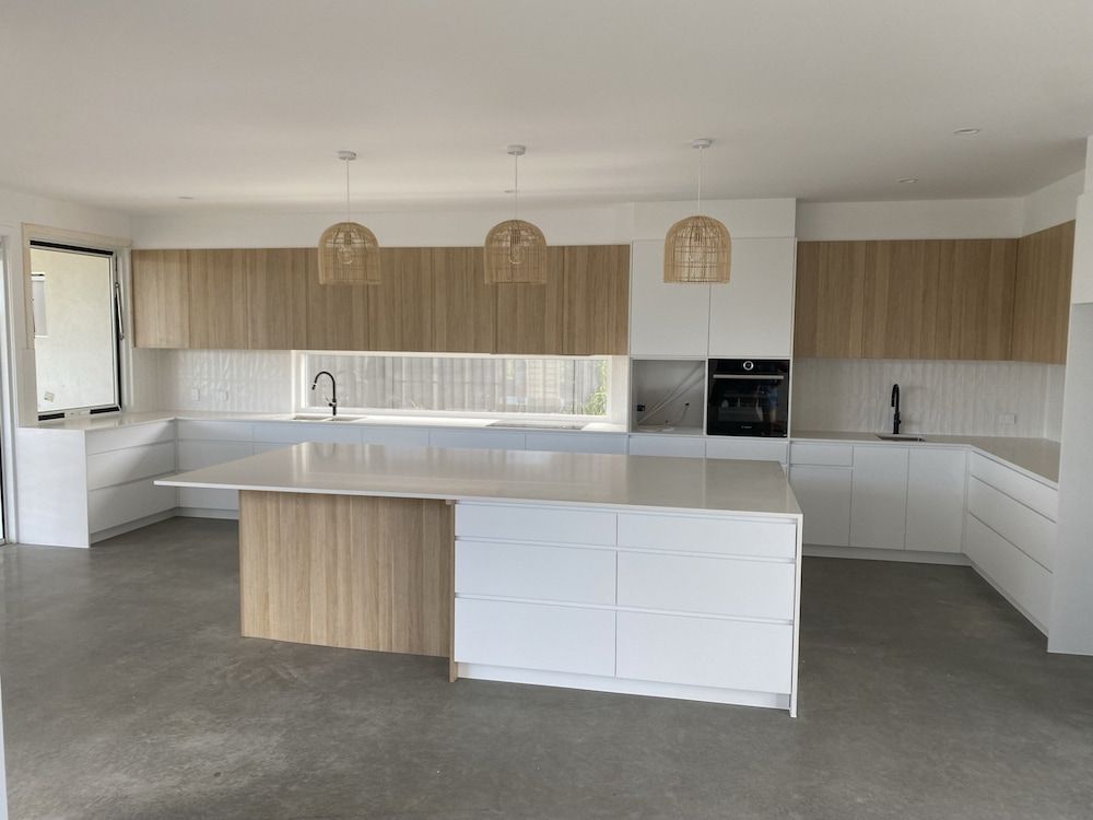 A Kitchen With White Cabinets And A Large Island In The Middle — Cross Cabinets In Maroochydore, QLD
