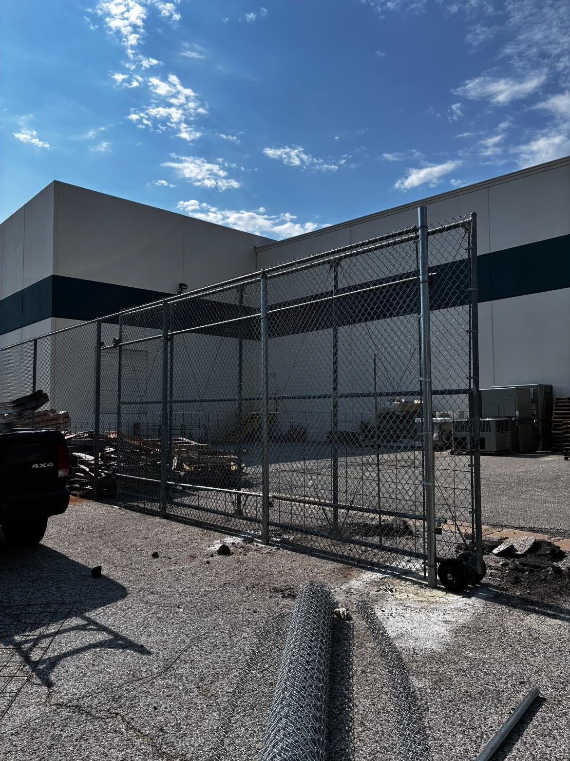 A forklift is parked in a warehouse behind a chain link fence.