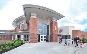 Modern brick building entrance with curved roof and a few people walking outside