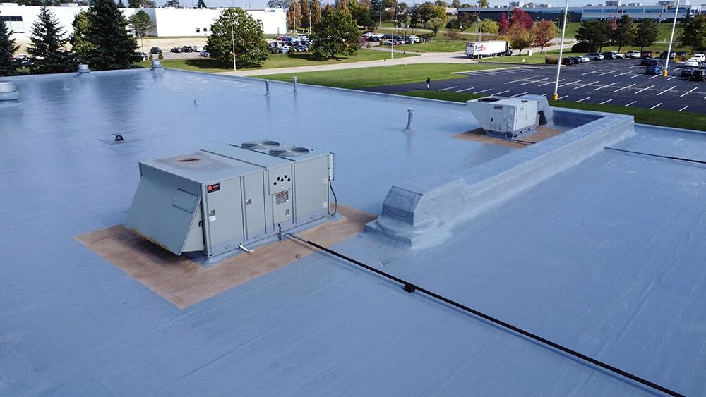 Blue flat rooftop with HVAC units and vents on a commercial building.