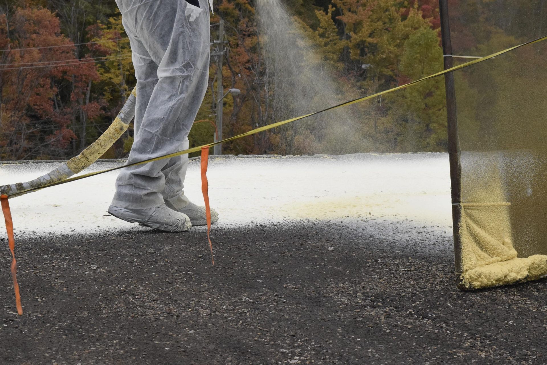 Person in gray pants and sneakers walking on a paved path beside a yellow rope barrier outdoors