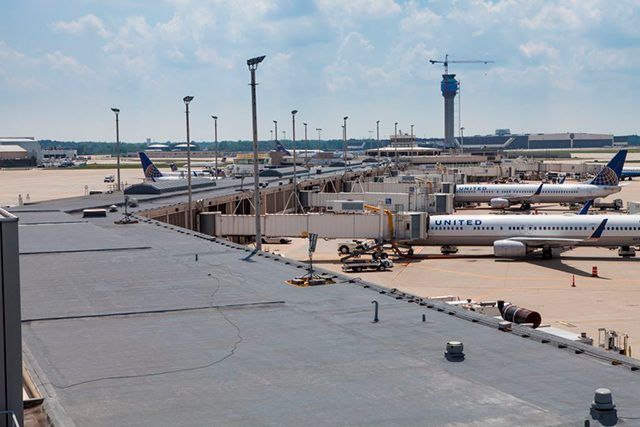 Airport tarmac with parked planes and terminal buildings under a clear sky