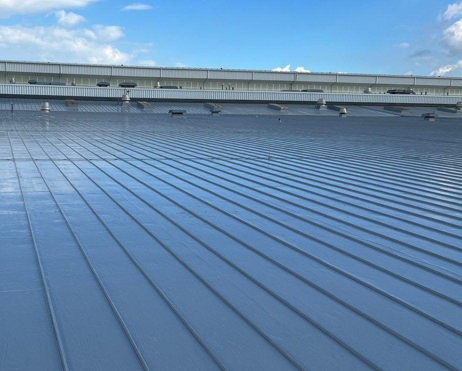 Blue corrugated metal roof with a long ridge under a clear sky